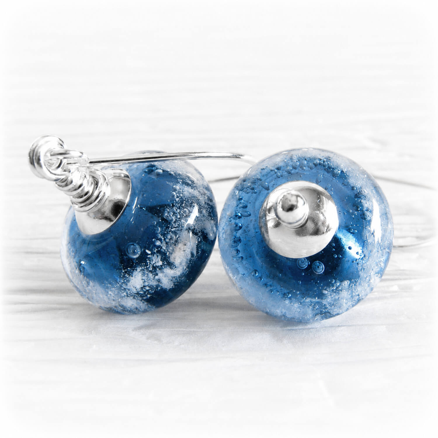 Orb-shaped memorial earrings featuring a blue and white swirling glass bead with a silver end cap