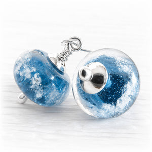 Round blue galaxy cremation glass earrings accented with polished silver decorative bead caps