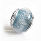 Hand blown glass cremation bead with personalized sterling silver bead caps on a white background 
