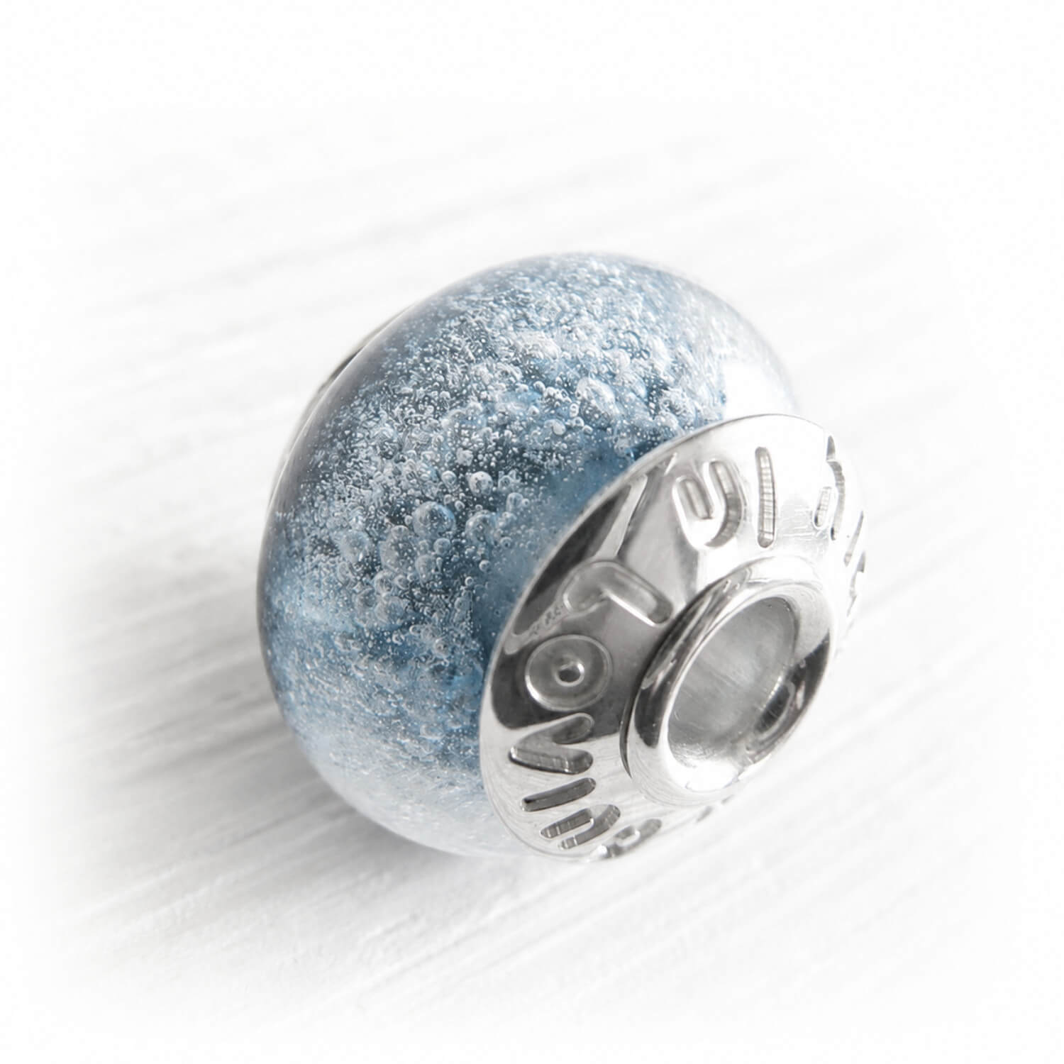 Custom engraved memorial bead caps on a blue glass cremation bead