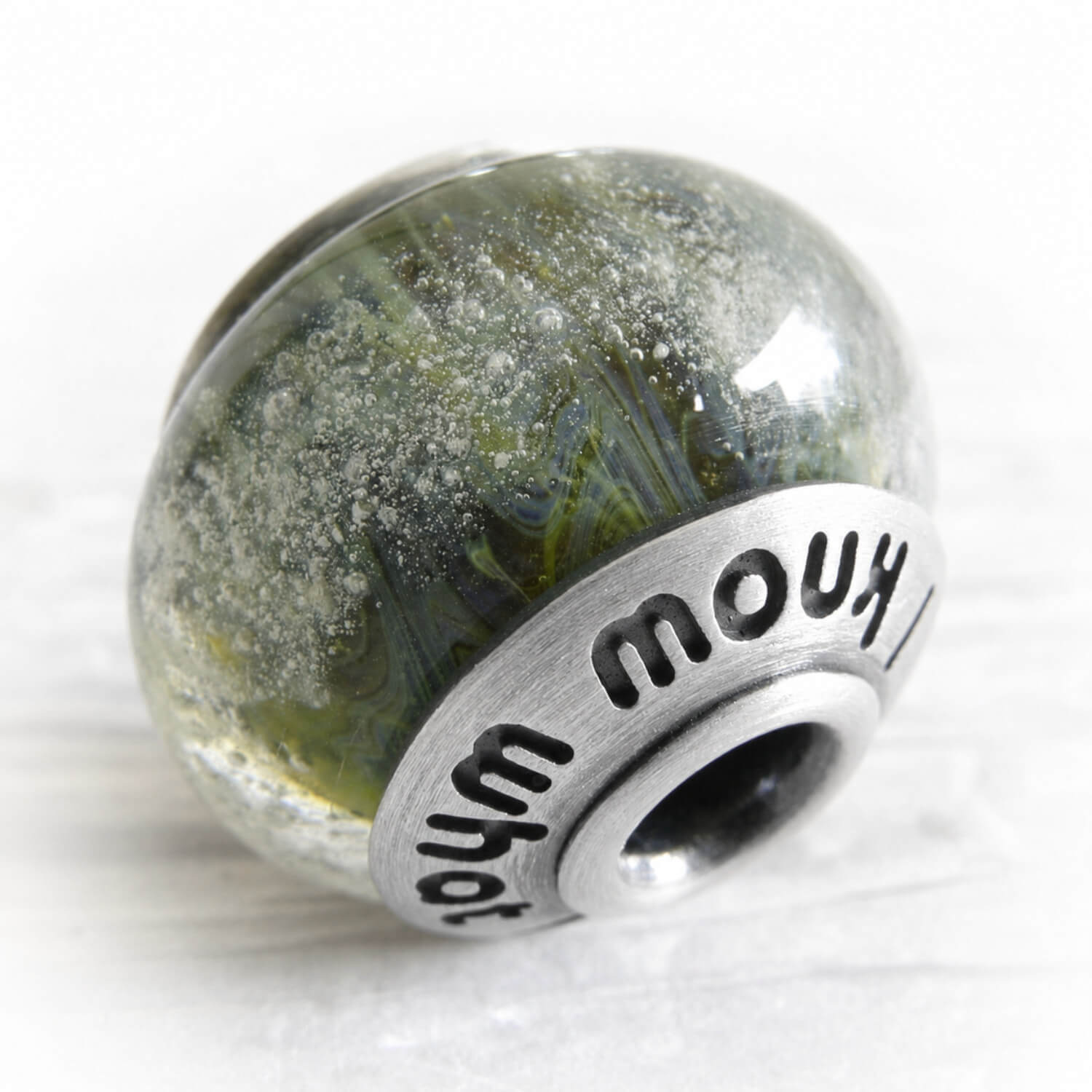 Green and blue glass bead encased  with floating cremation ashes 