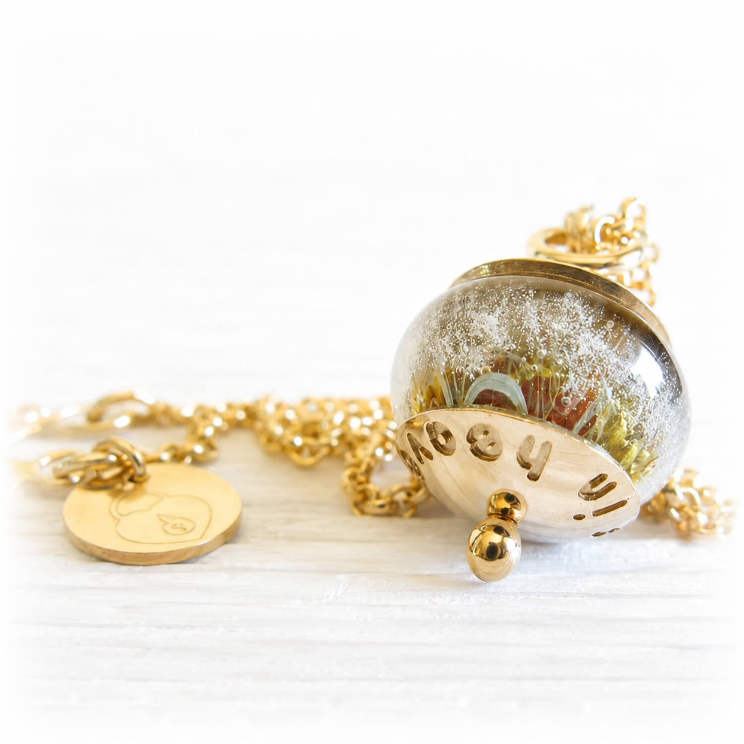 Cremation ash necklace charm with polished gold decorative caps and an amber and yellow hand blown glass bead