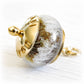 Gold engraved memorial charm bead featuring swirling white cremation ashes over an amber and tan glass core