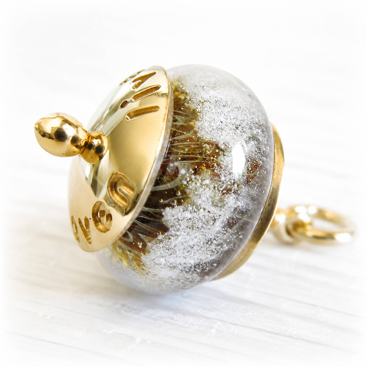 Gold engraved memorial charm bead featuring swirling white cremation ashes over an amber and tan glass core