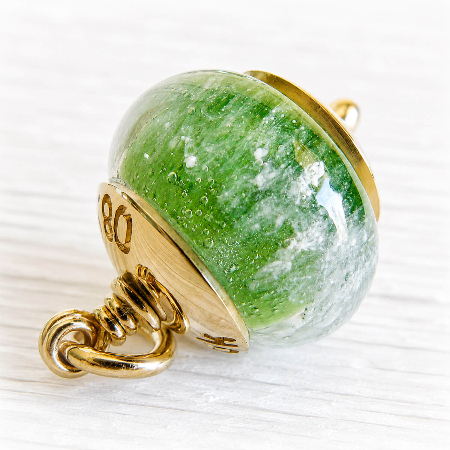 Green hand blown glass bead with encased pet ashes in a gold setting 