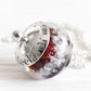 Deep red lamp-work cremation bead with encased ashes set in a sterling silver pendant