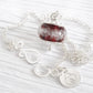 Deep red hand-crafted memorial bead with encased ashes set in sterling silver on a white background