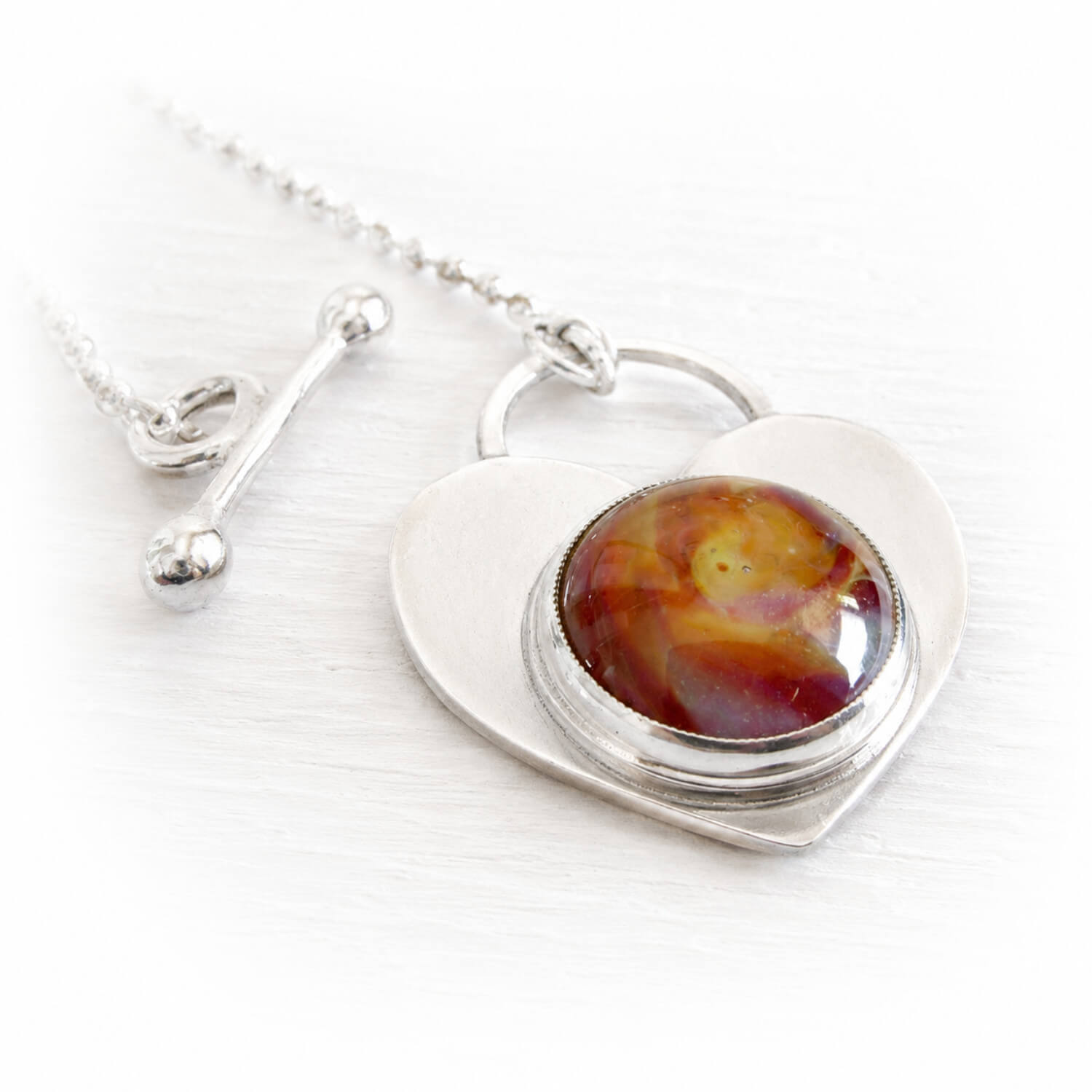 Sterling silver necklace with a heart-shaped pendant featuring ashes permanently encased in glass