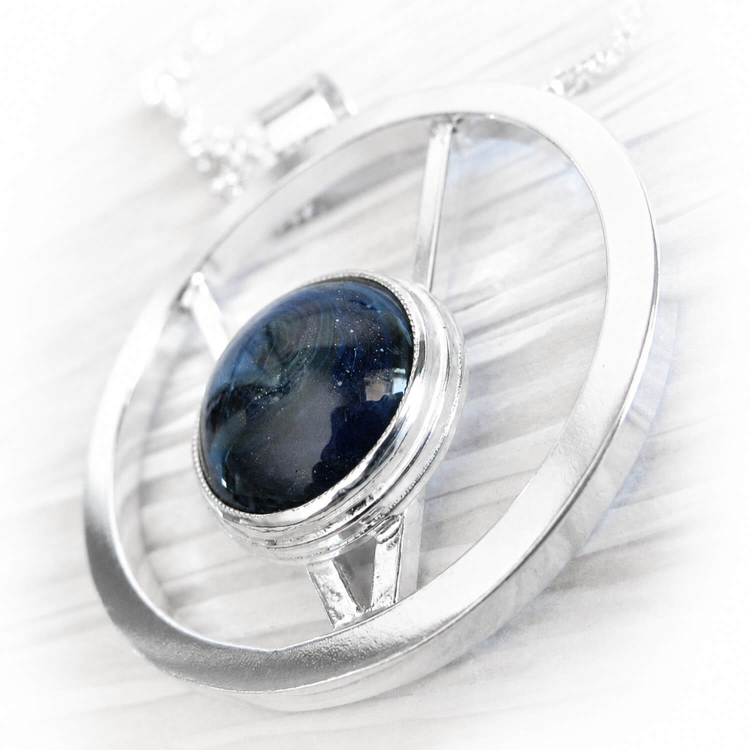 Hand forged sterling silver pendant with cremation ashes sealed within blue hand blown glass 
