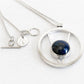 Hand forged sterling silver memorial necklace with a Locked In Art logo tag featuring an ash infused blue glass centerpiece 