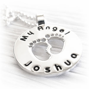 Silver pendant with footprints and engraved personalized text on a white background