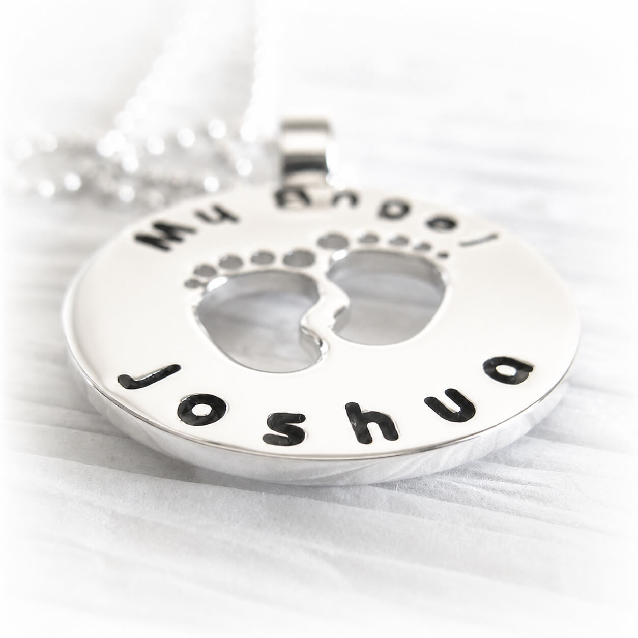 Remembrance pendant with 'Joshua' engraved below two foot prints made from sterling silver