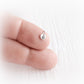 Small silver paw print charm on a finger against a white background