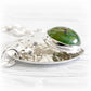 A hand forged sterling silver bracelet focal piece featuring a green hand blown glass cremation gem