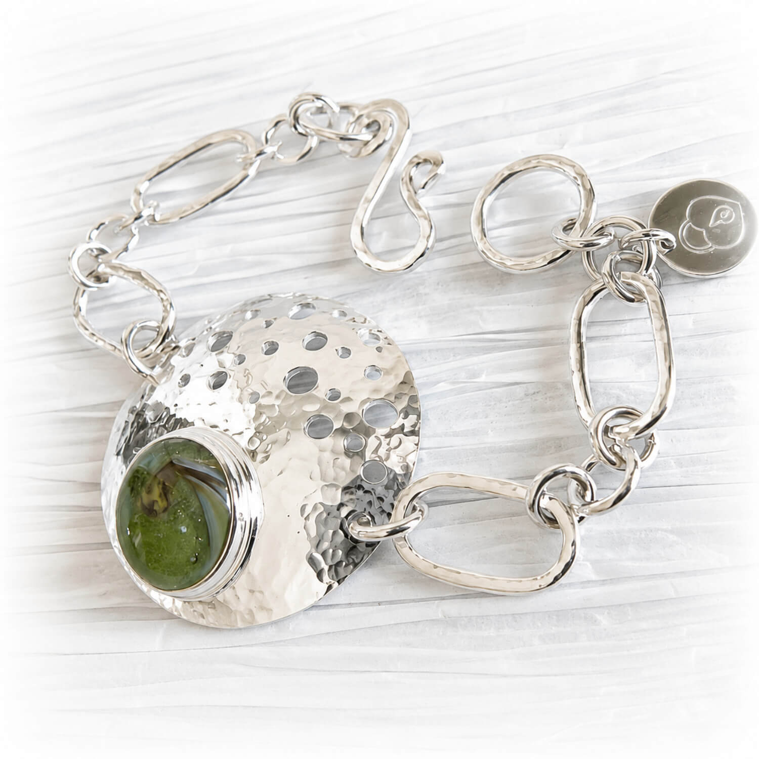 Polished sterling silver memorial bracelet featuring hand blown green glass with cremation ashes sealed within the glass