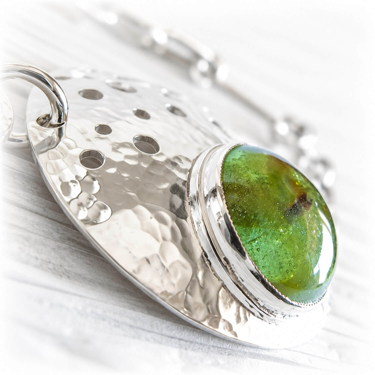 Green glass handcrafted with cremation ashes set onto a sterling silver remembrance keepsake