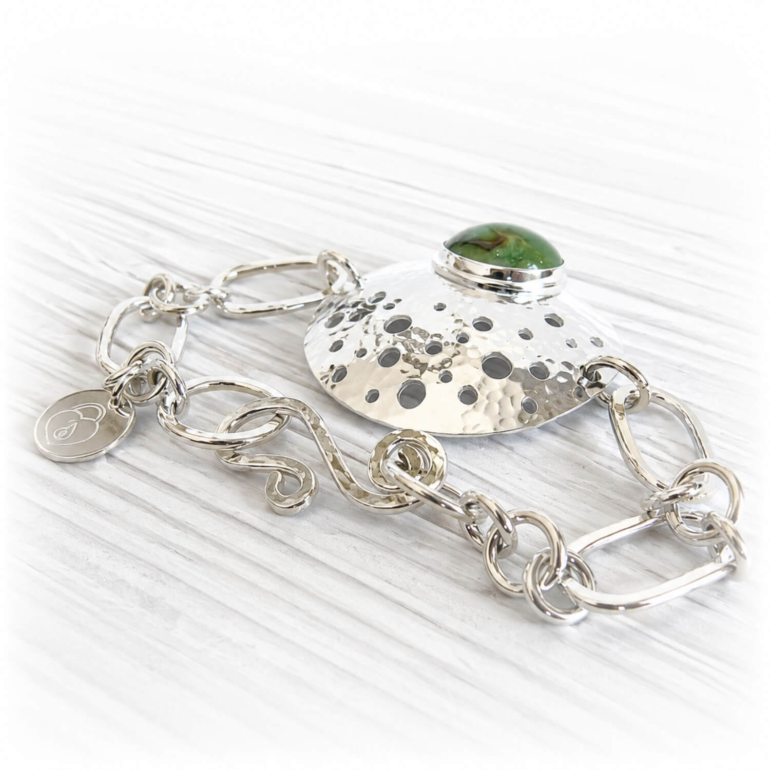 Hand forged commemorative bracelet displaying a green hand blown glass center piece infused with ashes