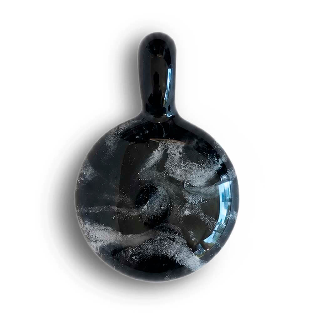 Swirls of white cremation ashes encased in a memorial pendant made from black hand blown glass
