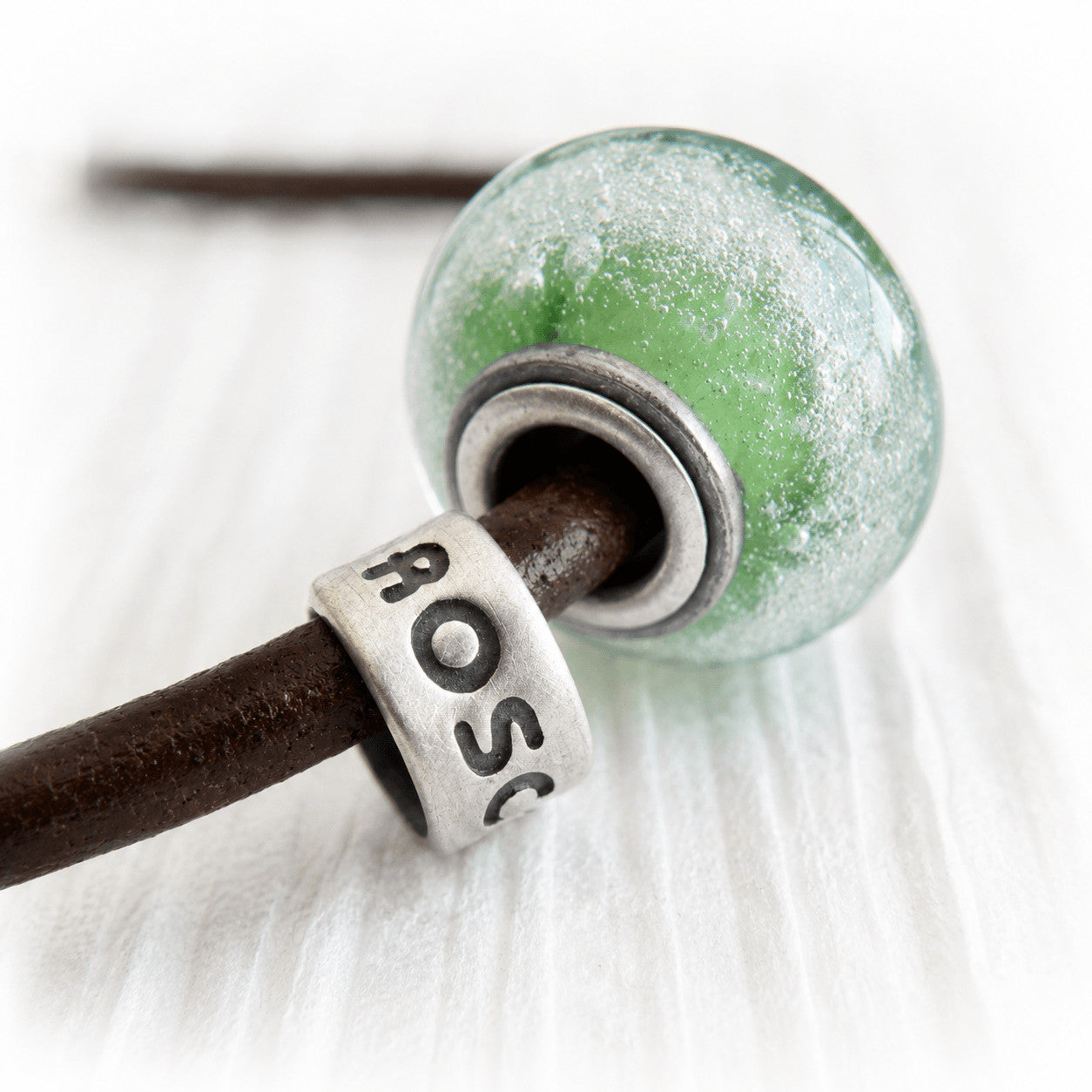 Custom engraved sterling silver slider beads with a green hand blown glass memorial bead and a brown leather bracelet 