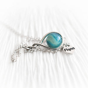 Memorial necklace with an aqua colored cremation glass marble and a tiny personalized heart charm