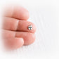 Small silver charm with 'Flynn' and a tiny paw print engraved sitting on a person's finger.