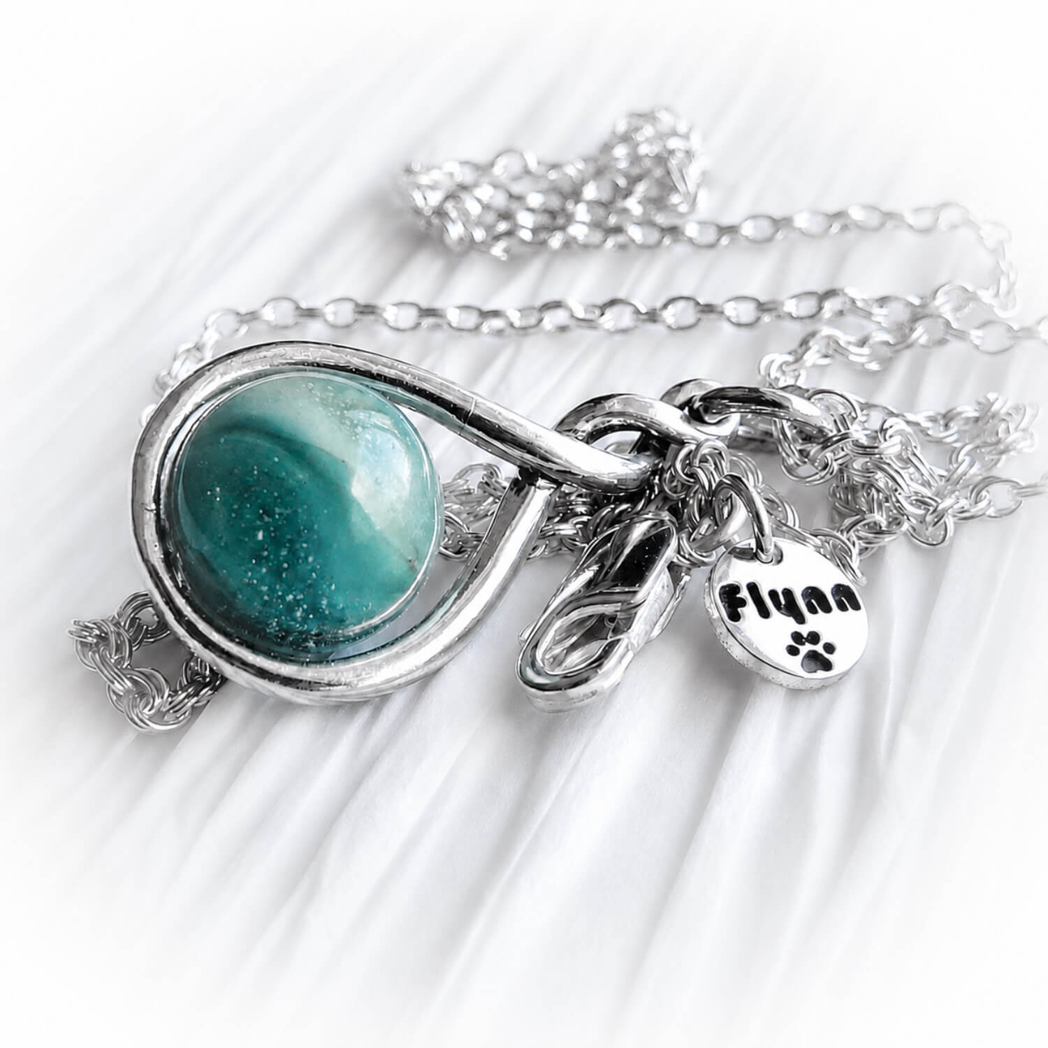 Sterling silver memorial necklace with a teal and aqua cremation marble and a custom engraved silver tag